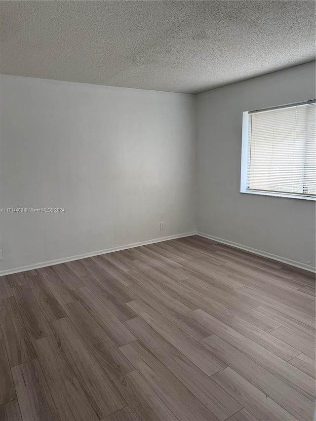 unfurnished room featuring light hardwood / wood-style floors and a textured ceiling