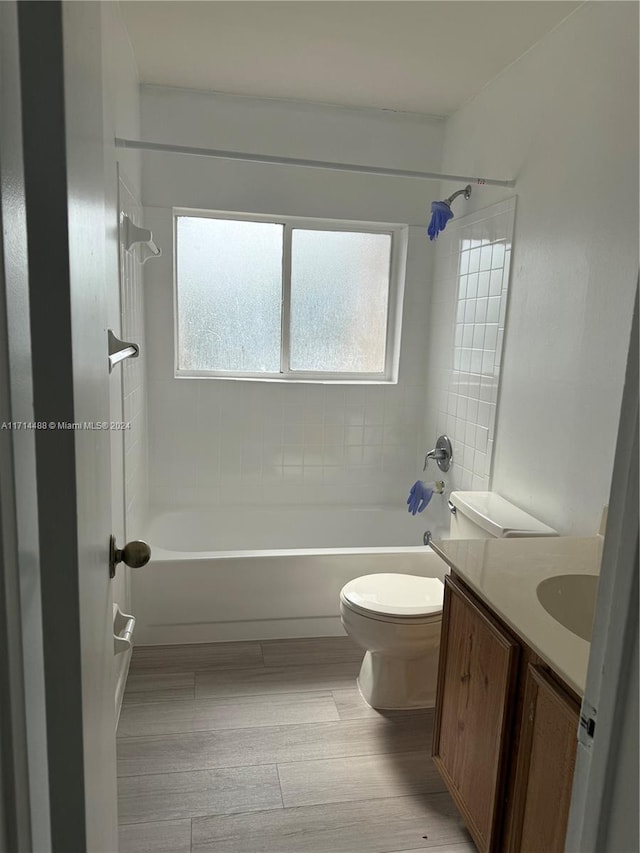 full bathroom with vanity, wood-type flooring, tiled shower / bath combo, and toilet