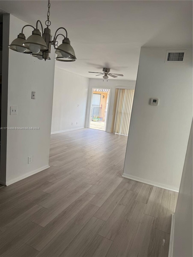 unfurnished room with wood-type flooring and ceiling fan with notable chandelier