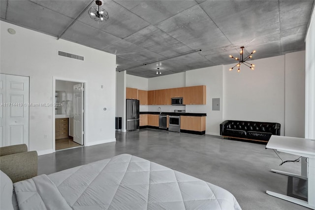 bedroom featuring an inviting chandelier, ensuite bath, a towering ceiling, concrete flooring, and stainless steel refrigerator