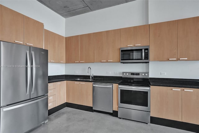 kitchen with dark stone counters, sink, a towering ceiling, and stainless steel appliances