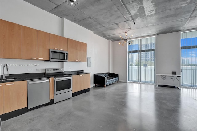 kitchen with a chandelier, appliances with stainless steel finishes, concrete flooring, and sink