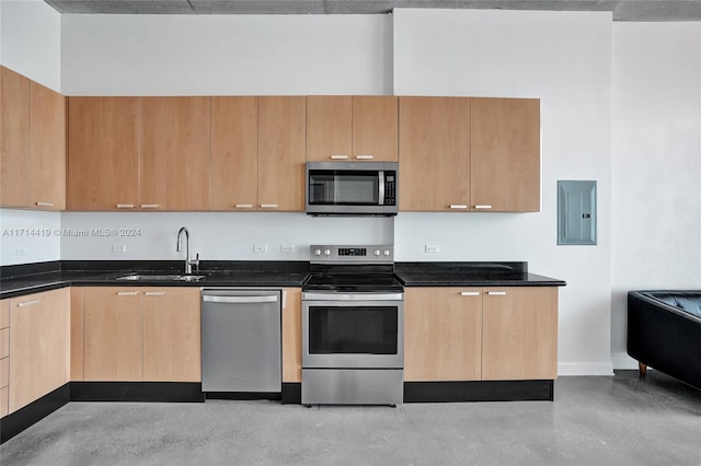 kitchen with sink, electric panel, dark stone countertops, light brown cabinetry, and appliances with stainless steel finishes