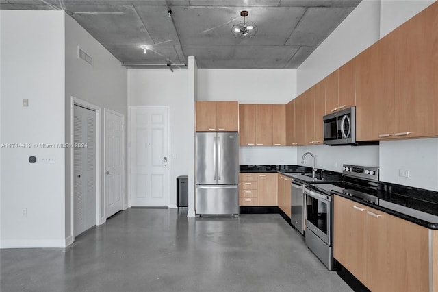 kitchen with dark stone countertops, sink, a towering ceiling, and stainless steel appliances