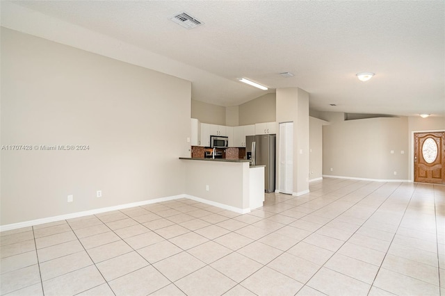 unfurnished living room with lofted ceiling, a textured ceiling, and light tile patterned floors