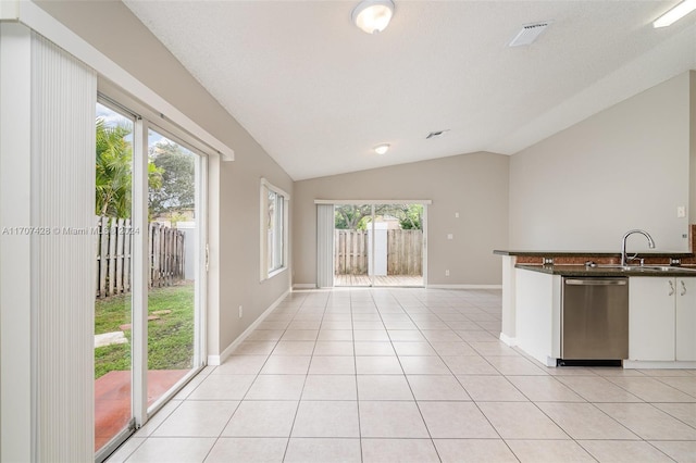 kitchen featuring sink, light tile patterned floors, dishwasher, white cabinetry, and lofted ceiling