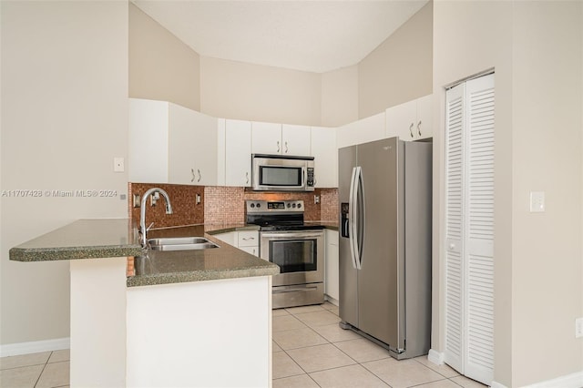 kitchen featuring stainless steel appliances, sink, light tile patterned floors, a high ceiling, and white cabinetry