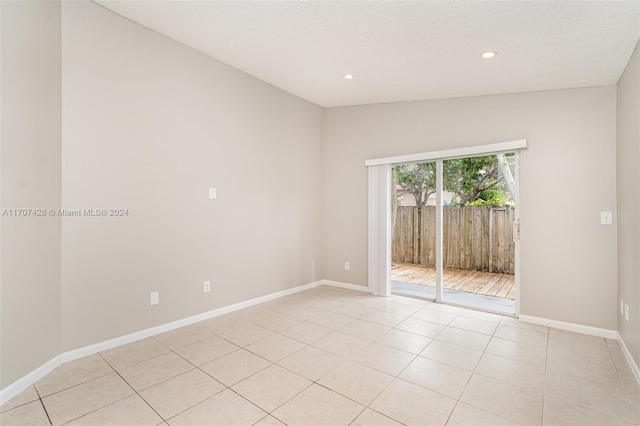 tiled spare room with a textured ceiling and vaulted ceiling