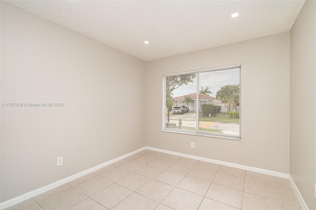 tiled empty room featuring a textured ceiling