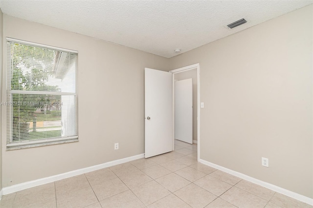 unfurnished room with light tile patterned floors and a textured ceiling