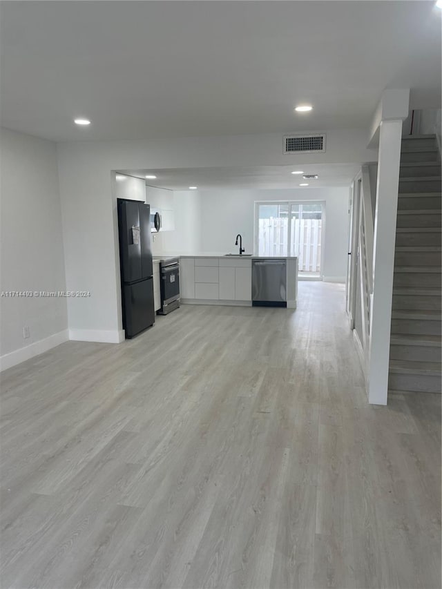 unfurnished living room with sink and light hardwood / wood-style flooring