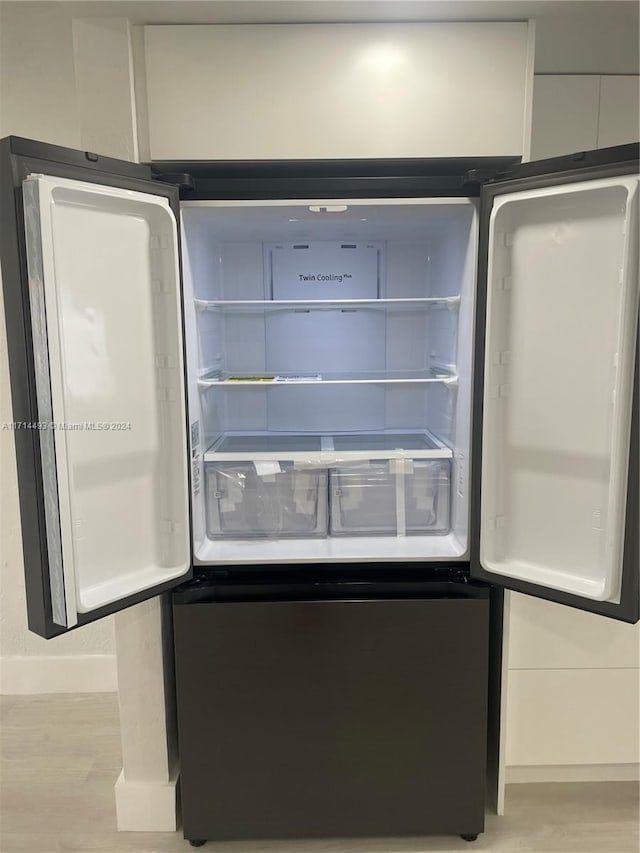 details with white cabinets, refrigerator, and light wood-type flooring