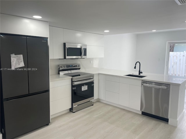 kitchen with kitchen peninsula, sink, white cabinets, and stainless steel appliances