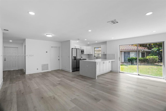 kitchen with kitchen peninsula, white cabinetry, a healthy amount of sunlight, and appliances with stainless steel finishes