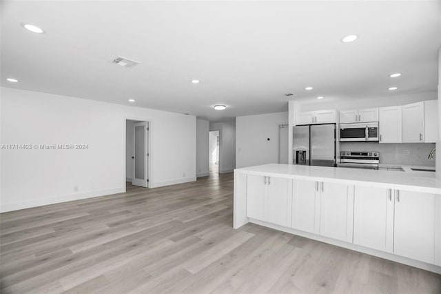 kitchen featuring white cabinetry, sink, stainless steel appliances, light hardwood / wood-style flooring, and kitchen peninsula