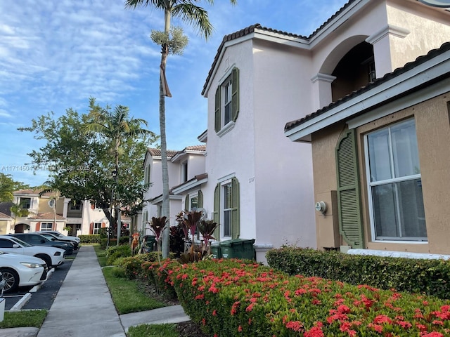 view of side of property with a residential view, stucco siding, and a tile roof