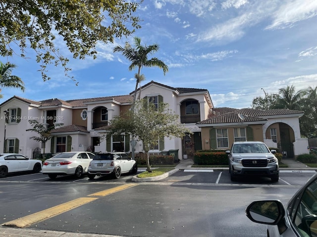 view of front facade featuring stucco siding, uncovered parking, and a tile roof