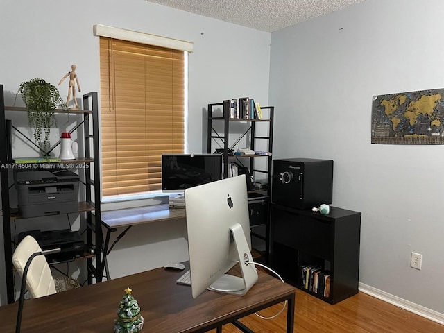 home office featuring a textured ceiling, baseboards, and wood finished floors