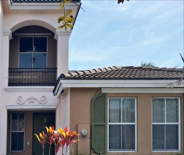 exterior space with a balcony, a tiled roof, and stucco siding