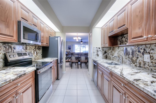 kitchen featuring light stone countertops, appliances with stainless steel finishes, backsplash, sink, and light tile patterned flooring