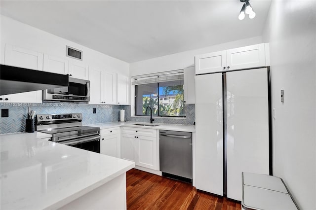 kitchen with dark wood-type flooring, sink, decorative backsplash, white cabinetry, and stainless steel appliances