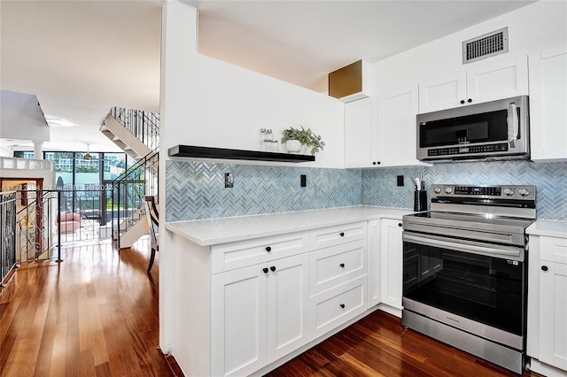 kitchen with tasteful backsplash, expansive windows, white cabinets, and appliances with stainless steel finishes