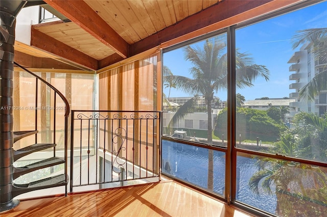 unfurnished sunroom with beam ceiling, wooden ceiling, and a healthy amount of sunlight