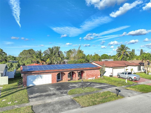 single story home featuring a garage, a front yard, and solar panels