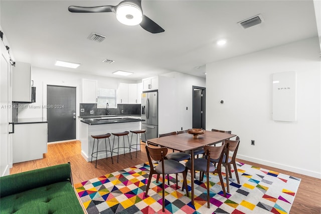 dining area with light hardwood / wood-style floors, ceiling fan, and sink