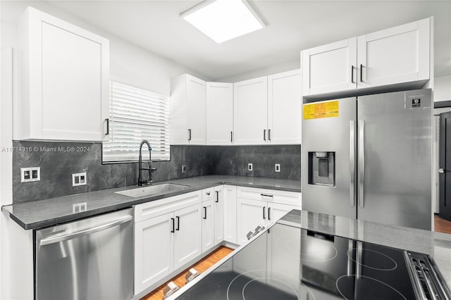 kitchen featuring white cabinets, sink, stainless steel appliances, and tasteful backsplash