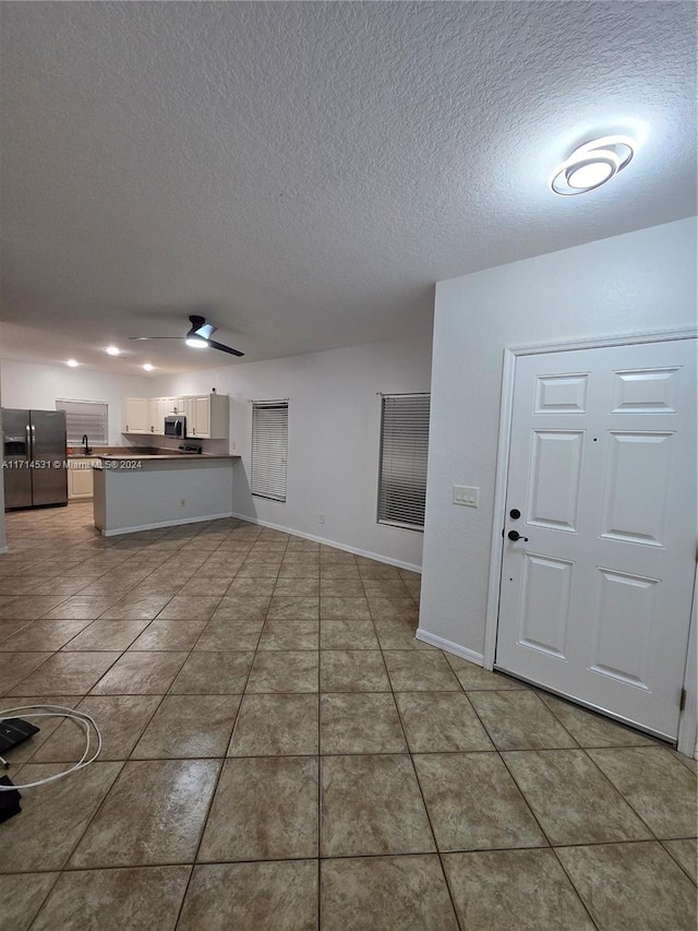 interior space with tile patterned flooring, ceiling fan, and a textured ceiling