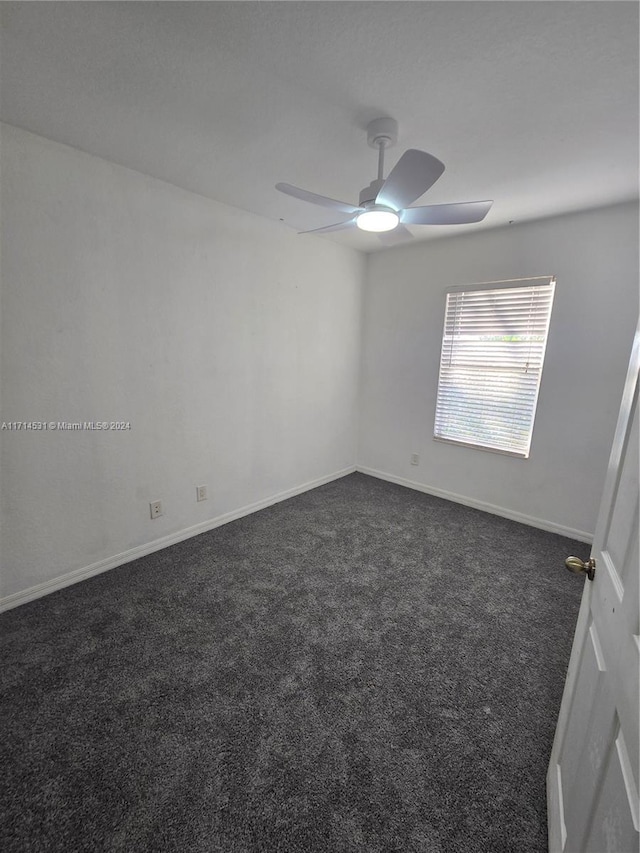 empty room with dark colored carpet and ceiling fan