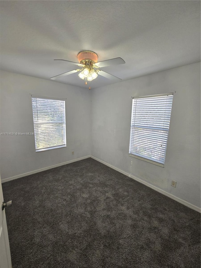 spare room with ceiling fan and dark colored carpet