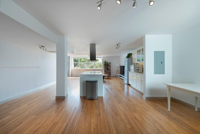 kitchen with rail lighting, light hardwood / wood-style floors, exhaust hood, electric panel, and white cabinetry