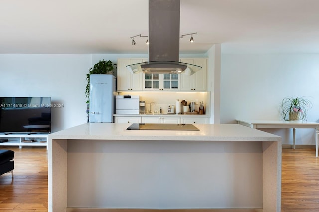 kitchen with sink, island range hood, a kitchen island with sink, and black electric cooktop