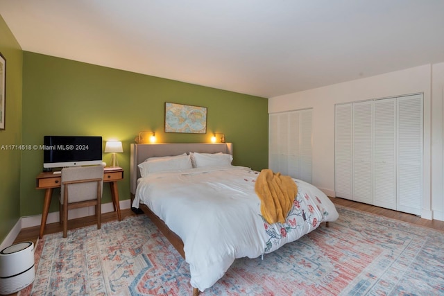 bedroom with hardwood / wood-style floors and two closets