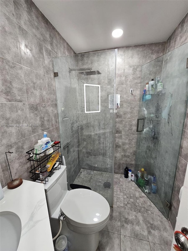 bathroom with sink, toilet, walk in shower, and tile walls