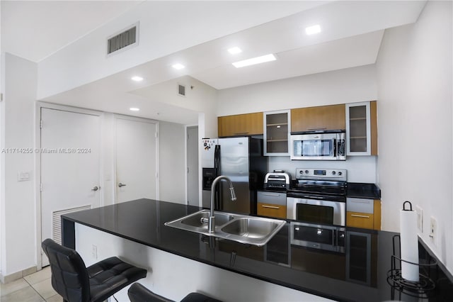 1750 N Bayshore Dr Unit 3210, Miami, FL 33132 - kitchen featuring stainless steel appliances, dark countertops, brown cabinets, a breakfast bar area, and glass insert cabinets