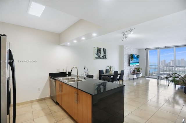 kitchen with floor to ceiling windows, sink, kitchen peninsula, light tile patterned floors, and appliances with stainless steel finishes