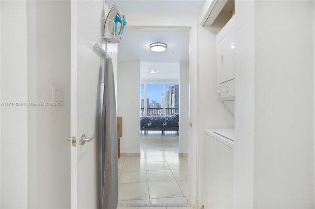 hall with stacked washer and dryer and light tile patterned floors