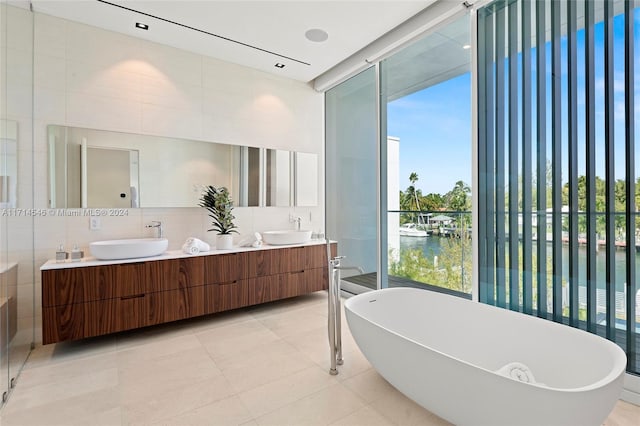 bathroom with vanity, a water view, tile walls, tile patterned flooring, and a bathing tub