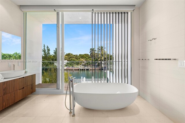 bathroom featuring vanity, a bathtub, a water view, and a healthy amount of sunlight