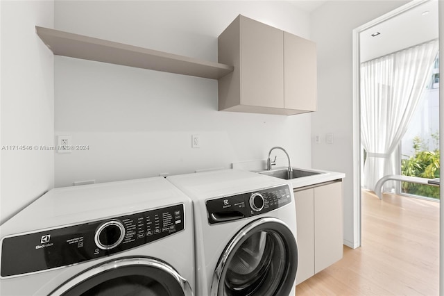 washroom featuring washer and dryer, light hardwood / wood-style floors, cabinets, and sink