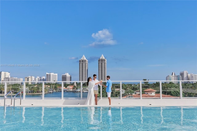 view of swimming pool with a water view and a view of the beach