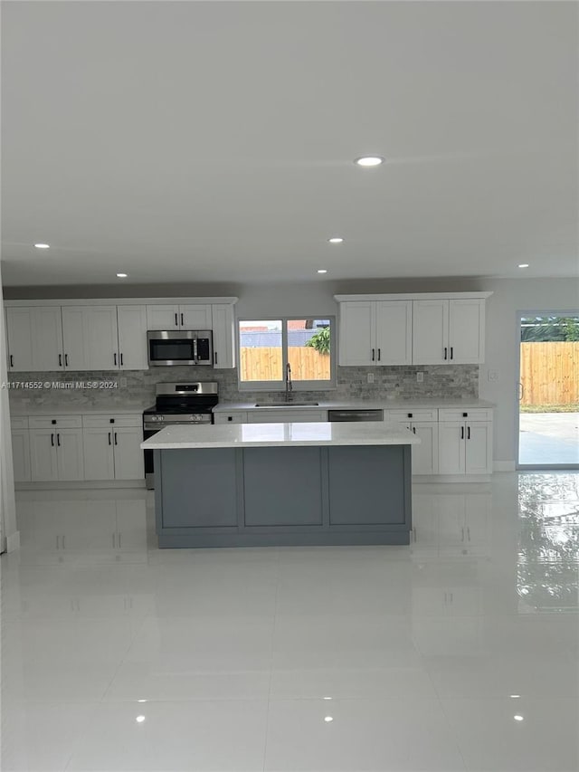 kitchen with sink, stainless steel appliances, white cabinetry, and light tile patterned flooring