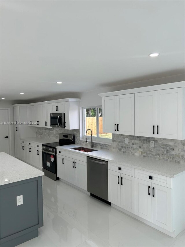 kitchen with sink, decorative backsplash, light stone countertops, white cabinetry, and stainless steel appliances