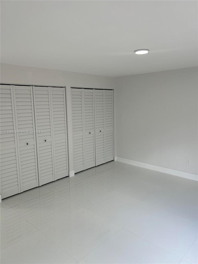 unfurnished bedroom featuring two closets and tile patterned floors