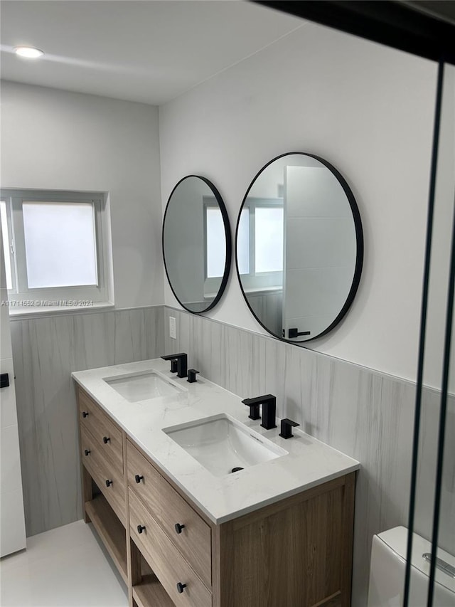 bathroom with a wealth of natural light, vanity, and tile walls