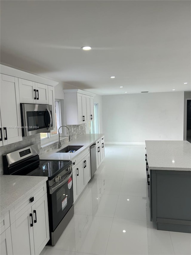 kitchen featuring sink, stainless steel appliances, light stone counters, backsplash, and white cabinets