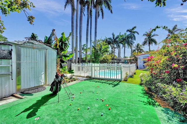 view of yard featuring a fenced in pool and a storage shed